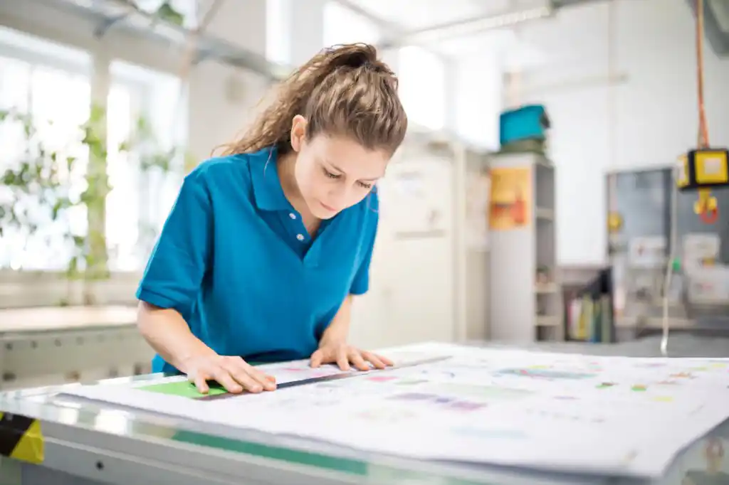 Femme travaillant sur la calibration des couleurs d'impression et la préparation du papier pour un projet.